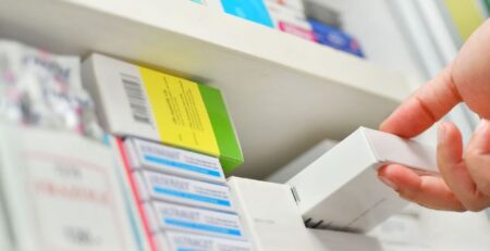 pharmacist pulling prescription from shelf